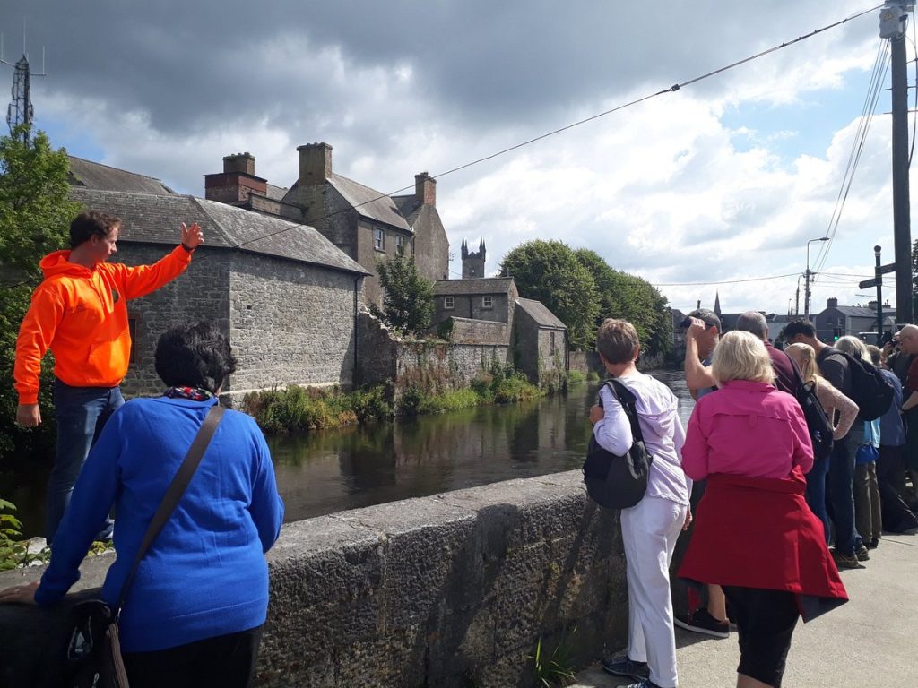 ollie-wearing-his-famous Tour guide showing group of tourists a landmark