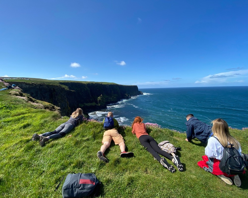 1-1 Group of tourist laying looking over cliffs of Moher