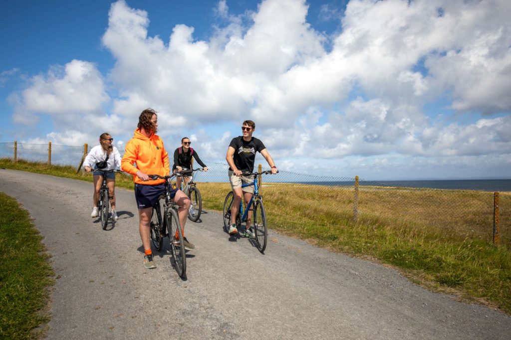 AKphoto (107) Group cycling on a coastal path under a bright blue sky, enjoying the scenic outdoor experience.