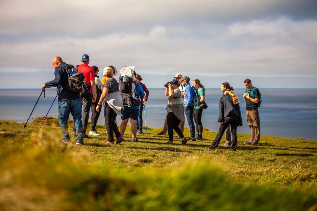 AKphoto (120) Group of hikers exploring a scenic coastal cliff trail with ocean views on a sunny day.