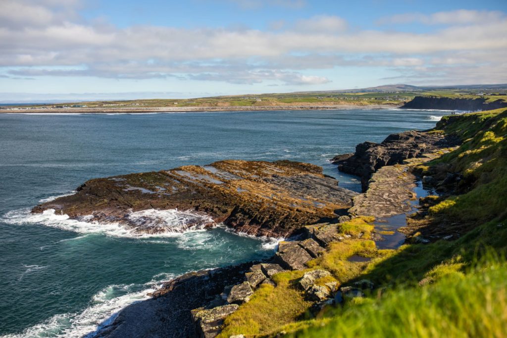 AKphoto (55) Rugged coastal landscape with lush green cliffs and blue ocean under a clear sky.
