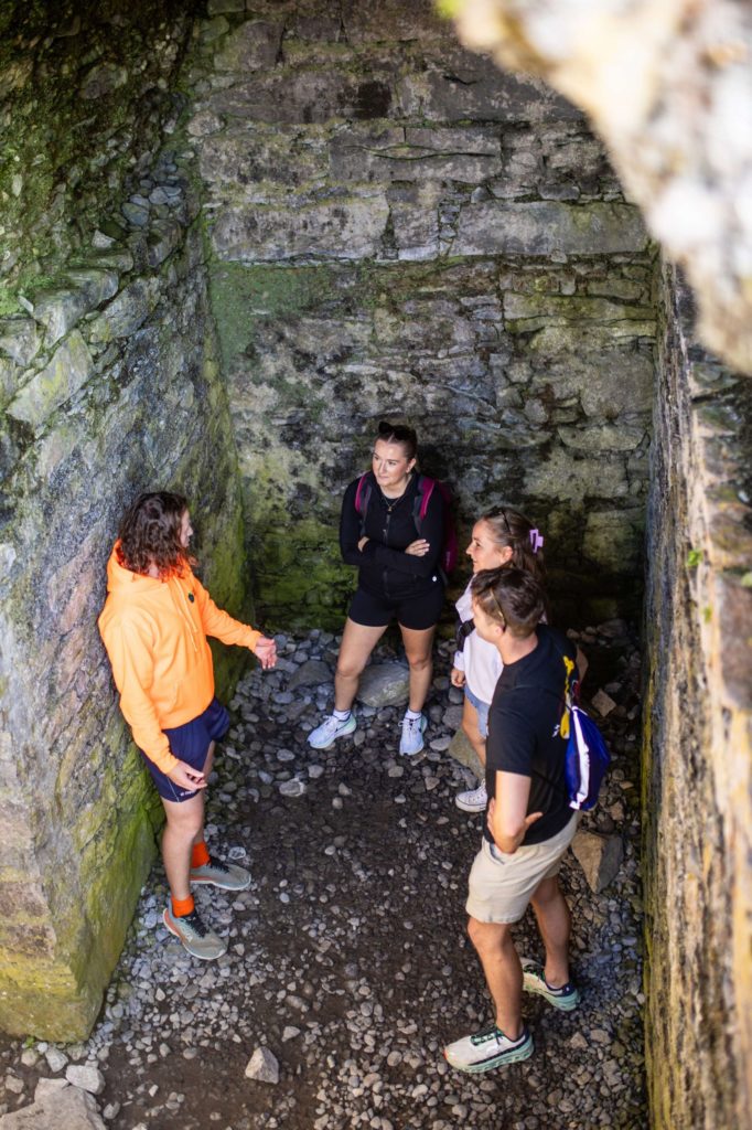 AKphoto (67) Group explores ancient stone structure in vibrant attire, engaging in lively conversation. Adventure in historical site.
