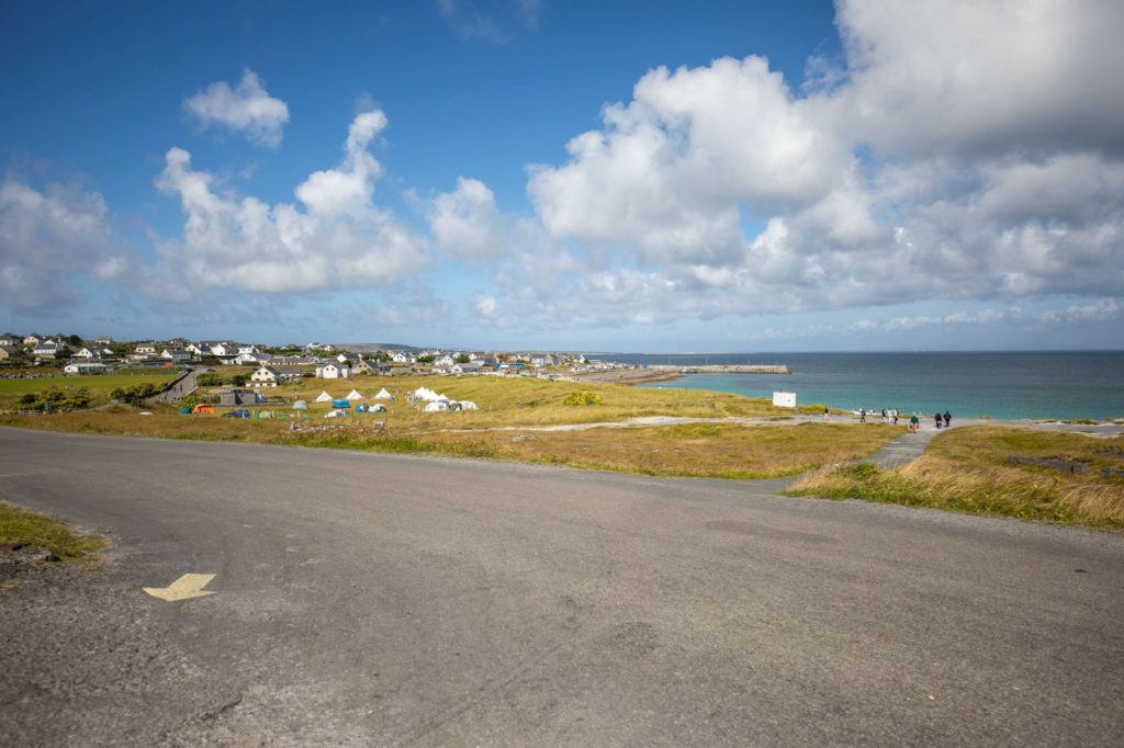 AKphoto (96) Coastal village with tents and cottages by the sea under a bright blue sky with clouds.
